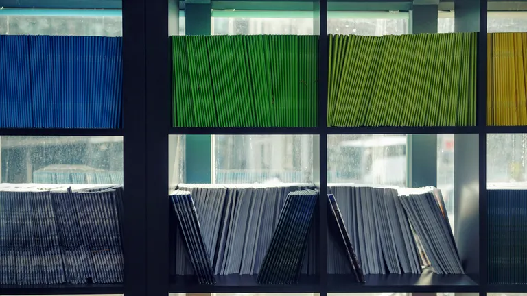 Black shelves with different color files stacked on them - white, blue, green, light green and yellow.