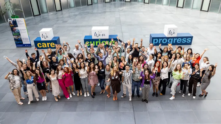 A group of students and mentors smile and pose happy, with their hands in the air towards the camera