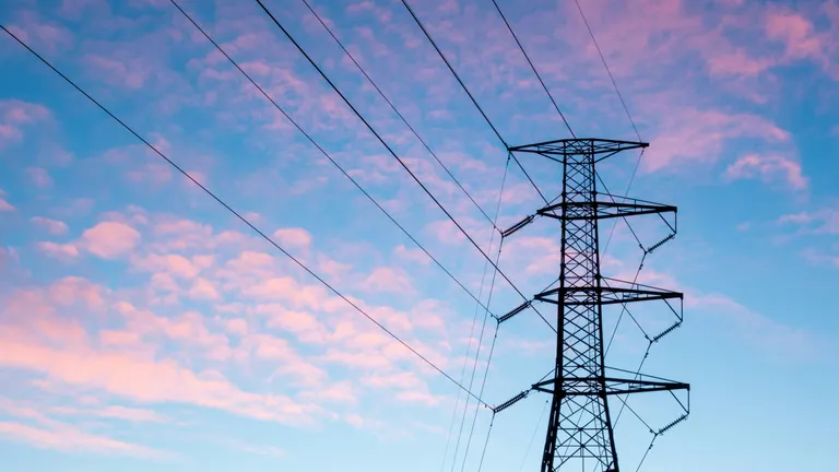 High voltage power pole seen from below with a pink and blue sky in the background